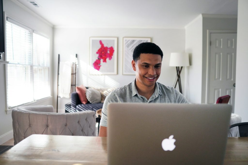 man-in-gray-hoodie-sitting-on-chair-in-front-of-silver-macbook